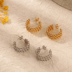 Twisted rope design earrings in gold and silver finish on textured paper background