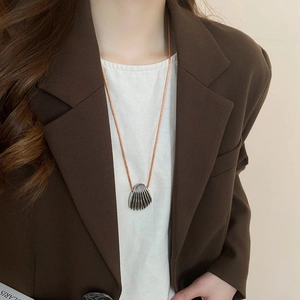 Detail of silver shell pendant necklace with brown cord on a brown blazer outfit