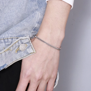 Close-up of silver mesh woven chain bracelet on model wrist with denim jacket