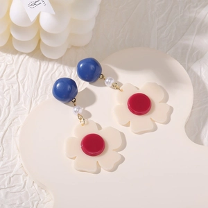 Close-up of fan-shaped pearl tassel earrings featuring blue beads and resin floral charms