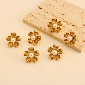 Vintage gold titanium steel flower earrings with white pearls on a stone backdrop