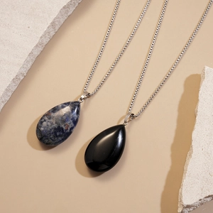 Detailed view of teardrop pendants in blue sodalite and black obsidian on metal chains