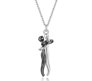 Macro detail of abstract embracing couple pendant in black and silver tone finish
