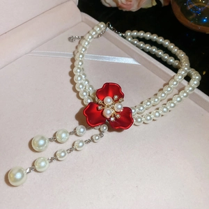 Detail of double-layer pearl necklace with red floral clover pendant and pearl fringe