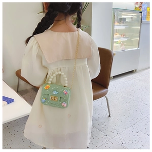 Detail of green girls' mini bag with pearl handle, gold chain and cute cartoon charms