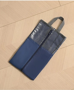Top view of blue travel shoe bag with grey mesh panel and handle on wooden floor