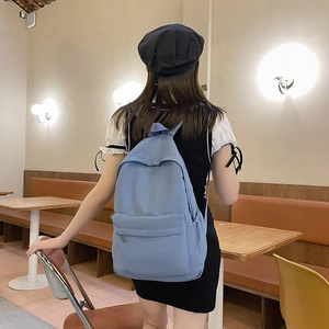Minimalist blue large capacity backpack for women shown in a cafe setting