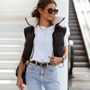Detail of a black quilted reversible vest with white lining and gold layered necklaces