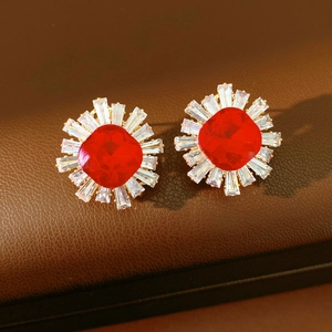 Macro shot of vintage sunburst earrings featuring a cushion-cut red stone in gold-tone metal
