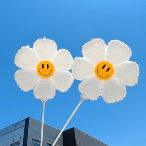 Daisy flower smile face foil balloons with white hand-held sticks against blue sky