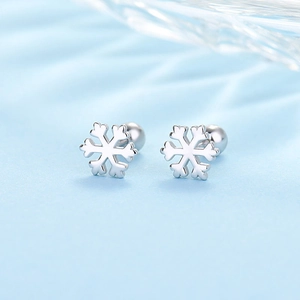 Macro shot of silver snowflake earrings with ball back closures on blue silk