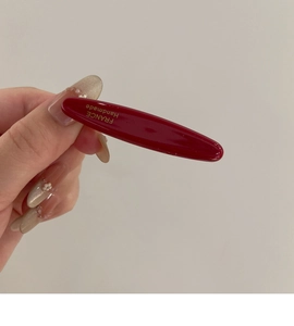Détail de la barrette ovale en acétate rouge foncé avec lettrage doré France Handmade