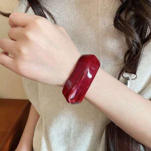Detail of reddish-brown acrylic marble bangle worn by a model in warm lighting