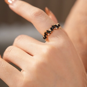 Macro shot of gold baguette ring with black stones and tiny white zircons on finger
