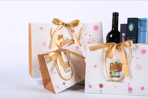 Three sizes of cartoon bear gift bags with golden ribbon bows and rope handles