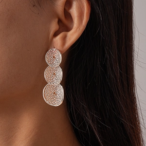 Detail of silver triple-layered hollow mesh geometric earrings worn by a model