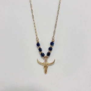 Macro detail of golden bull head pendant and blue beads on bohemian steel necklace
