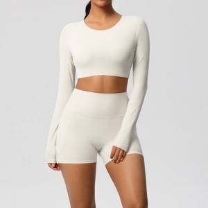 Detail van een crèmewitte yoga-set met crop top met lange mouwen en high waist korte broek