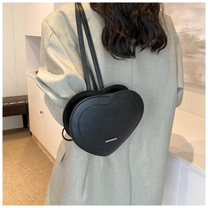 Detail of black heart-shaped backpack with sloh rabbit embossed pattern on grey blazer