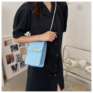 Detail of light blue quilted crossbody bag featuring gold twist lock and chain strap