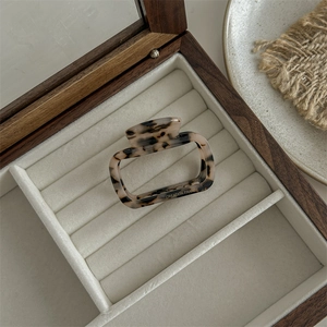 Detail of a square leopard print hair claw clip on a beige velvet jewelry box