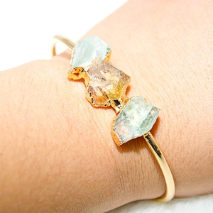 Detail of adjustable gold-plated cuff featuring raw amethyst and citrine stones on wrist