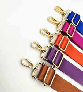 Detail of adjustable nylon straps in multiple colors with golden swivel metal hooks