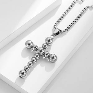 Polished stainless steel cross pendant necklace with beaded texture on white display