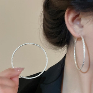 Large silver hoop earrings featuring minimalist metal wire wrap texture on model