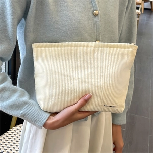 Chic beige corduroy cosmetic bag held by a model, showing soft texture and premium style