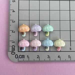 Detailed view of colorful 1.5cm resin mushroom charms on a measurement grid for DIY crafts