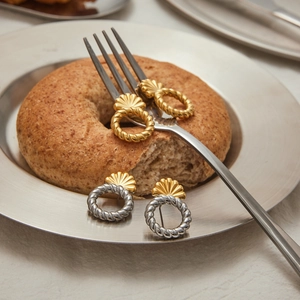 Dettaglio di orecchini a cerchio intrecciati oro e argento con borchie a conchiglia