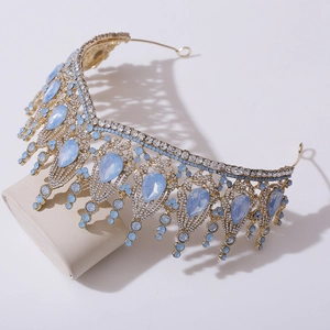 Detailed close-up of a baroque gold crown featuring large blue teardrop crystals and rhinestones