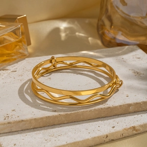 Detail showing high-polished golden double-layered bracelet with wavy and flat bands