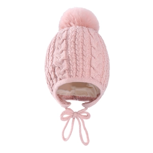 Detail of pink cable knit baby hat featuring a soft pompom and warm fleece lining