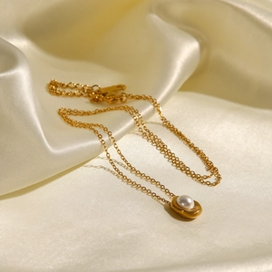 Elegante collana d'oro con perla e ciondolo ovale su seta color crema, stile minimalista