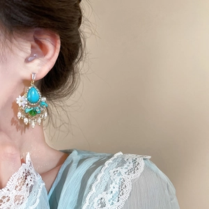 Detail view of ethnic style drop earrings with turquoise, pearls and floral tassels