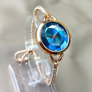 Detail of rose gold bracelet watch with blue geometric dial and rhinestone embellishments