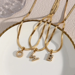Detail of 18K gold-plated flat snake chains with pearl-inlaid initial O, Z, and B pendants