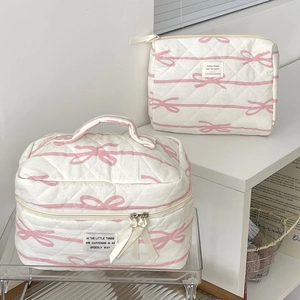 Set of two quilted white makeup bags featuring pink bows in large and small sizes