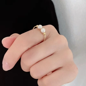 Elegant gold pearl ring with double white pearls on model's finger in minimalist setting