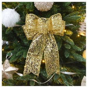 Close-up of sparkling champagne gold sequin bow hanging on a green Christmas tree branch