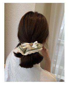 Close-up of green plaid lace hair scrunchie with cute bear ornament on a brown bun