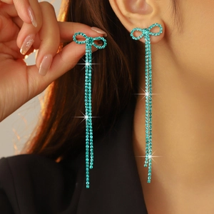 Blue rhinestone bow tassel drop earrings for bridal wear worn by a model in close-up
