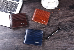 Three vintage wood-grain leather wallets in brown and navy on a professional business desk