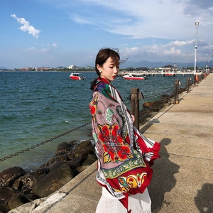 Detail of red ethnic floral silk scarf draped over shoulders at beach pier backdrop
