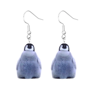 Macro detail of cute acrylic penguin earrings featuring high-gloss finish and silver hooks