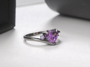 Macro shot of purple heart-shaped zircon ring with gunmetal finish and four-prong setting