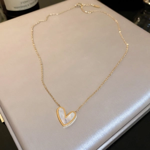 Close-up of golden stainless steel necklace featuring a white shell heart pendant