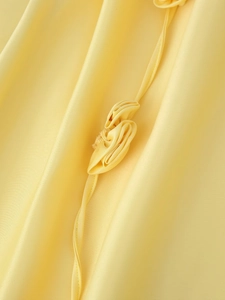 Détail d'une robe en satin jaune avec fleurs 3D et coutures précises sur le tissu